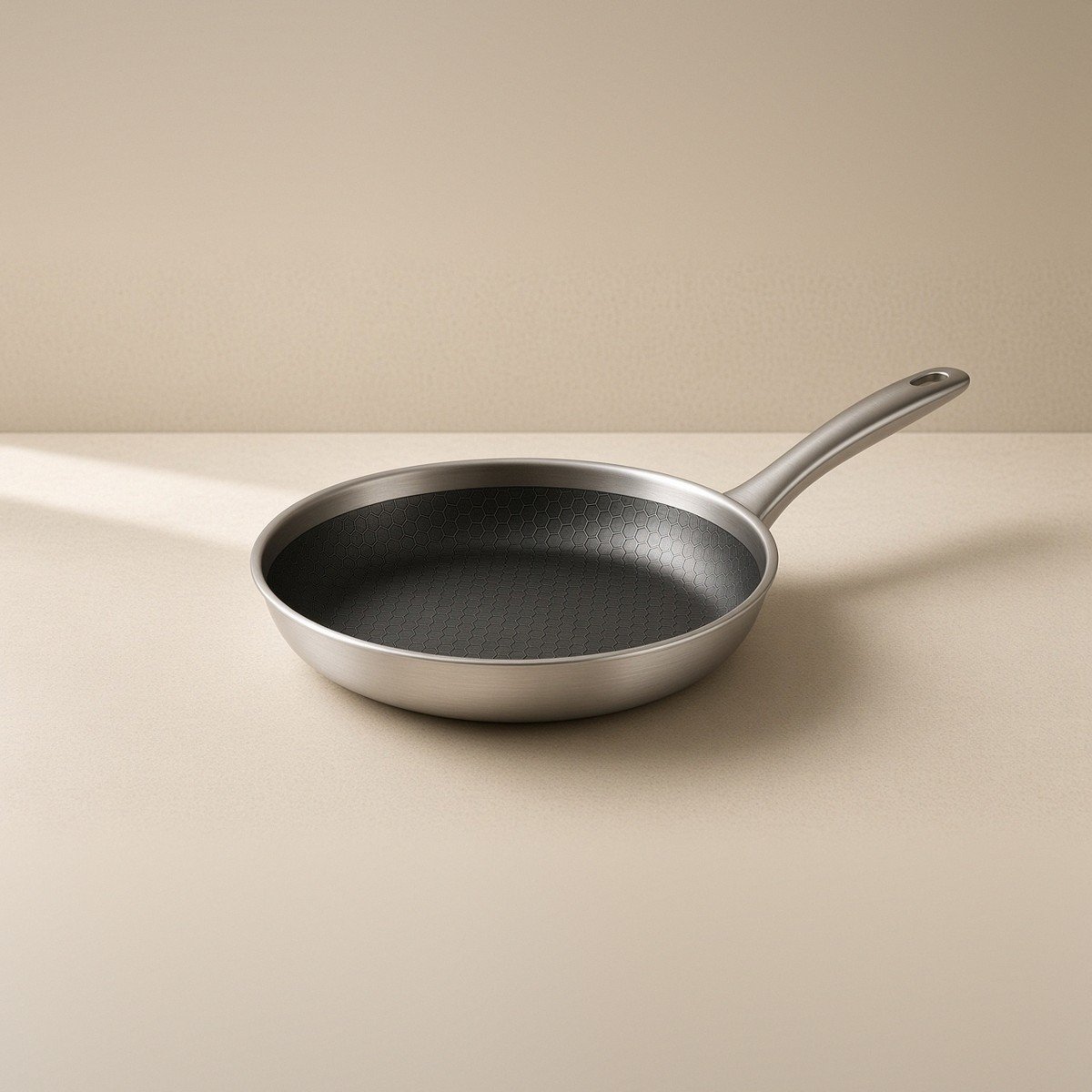 Three-quarter view: stainless body, dark textured surface, full handle on warm stone.